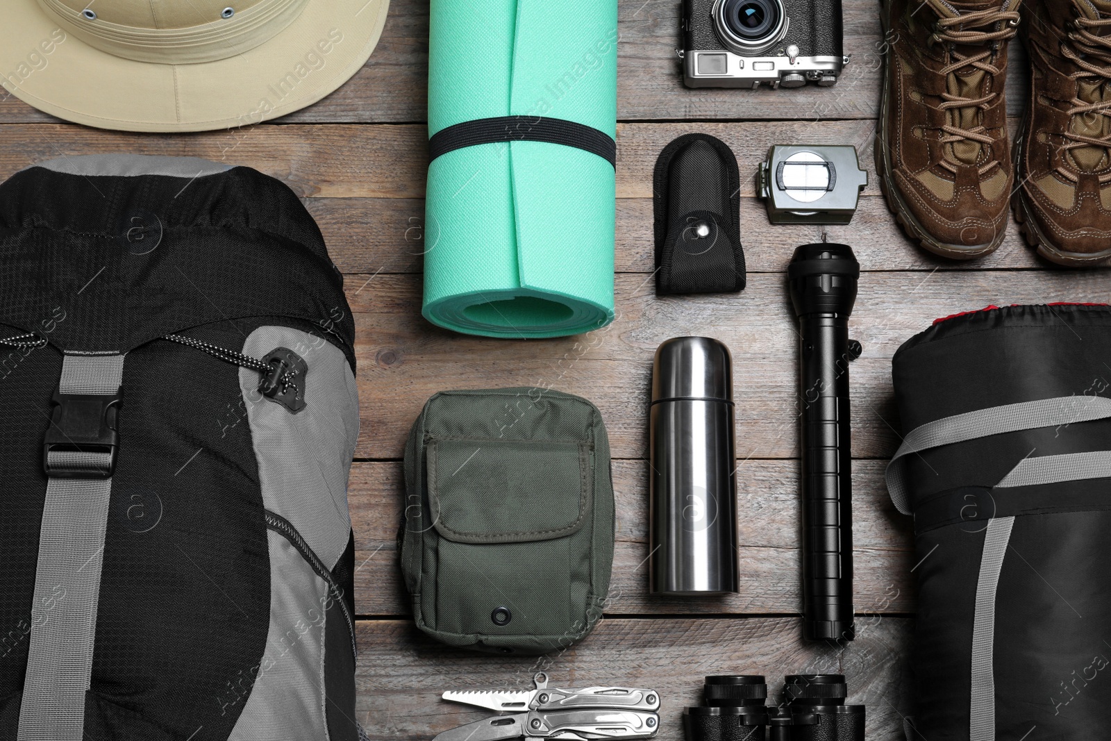 Photo of Flat lay composition with backpack and other different camping equipment for tourism on wooden background