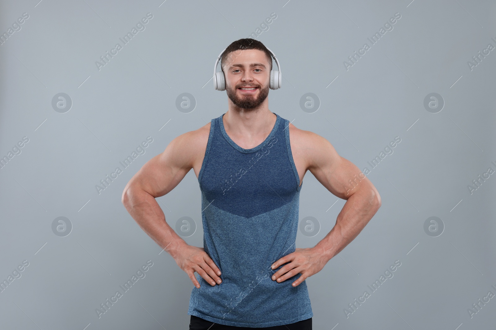 Photo of Handsome sportsman with headphones on grey background