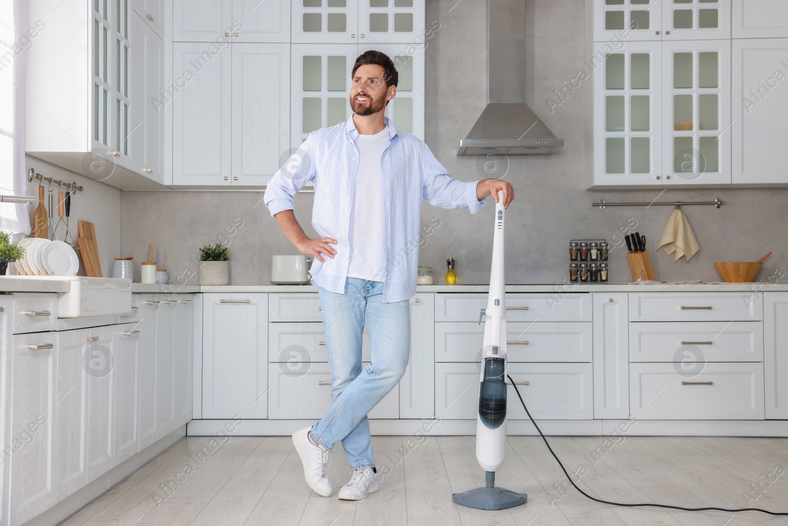 Photo of Happy man with steam mop in kitchen at home