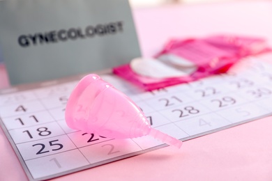 Menstrual cup and calendar on table. Gynecological care