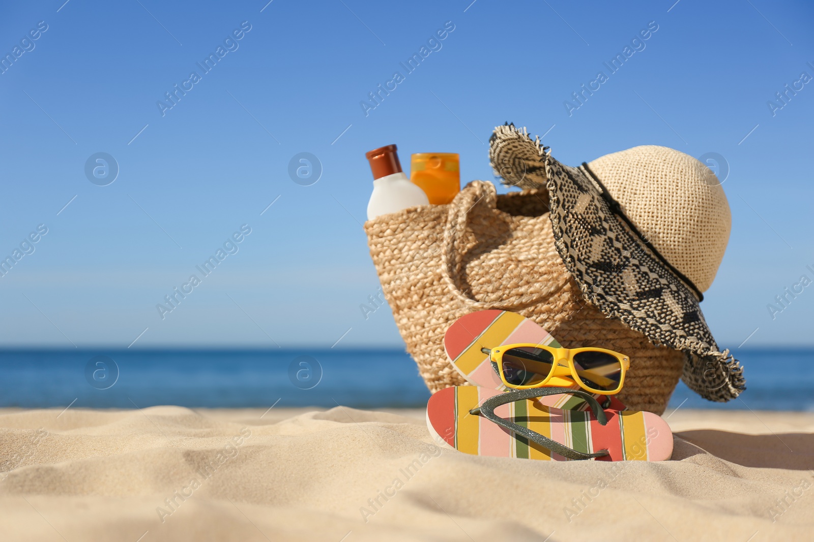 Photo of Stylish beach accessories for summer vacation on sand near sea. Space for text