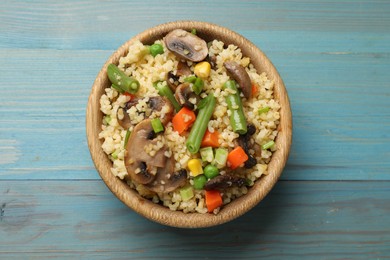 Photo of Delicious bulgur with vegetables and mushrooms on light blue wooden table, top view