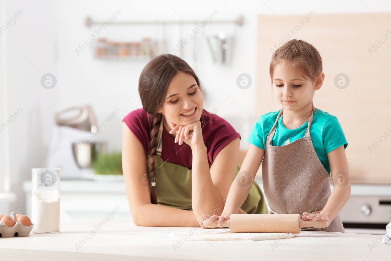 Photo of Mother and her daughter preparing dough at table in kitchen