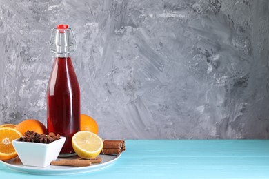 Bottle of aromatic punch drink and ingredients on light blue table, space for text