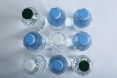 Photo of Rows of different plastic bottles with  water on white background, flat lay