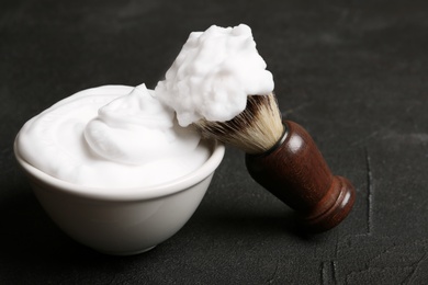 Photo of Shaving brush and bowl of foam on dark background