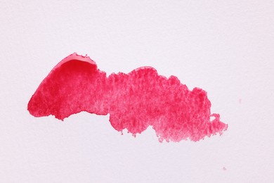 Photo of Blot of pink watercolor paint on white paper, top view