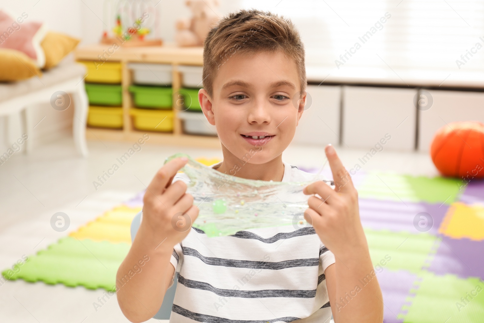 Photo of Little boy playing with slime in room