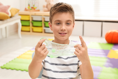 Photo of Little boy playing with slime in room