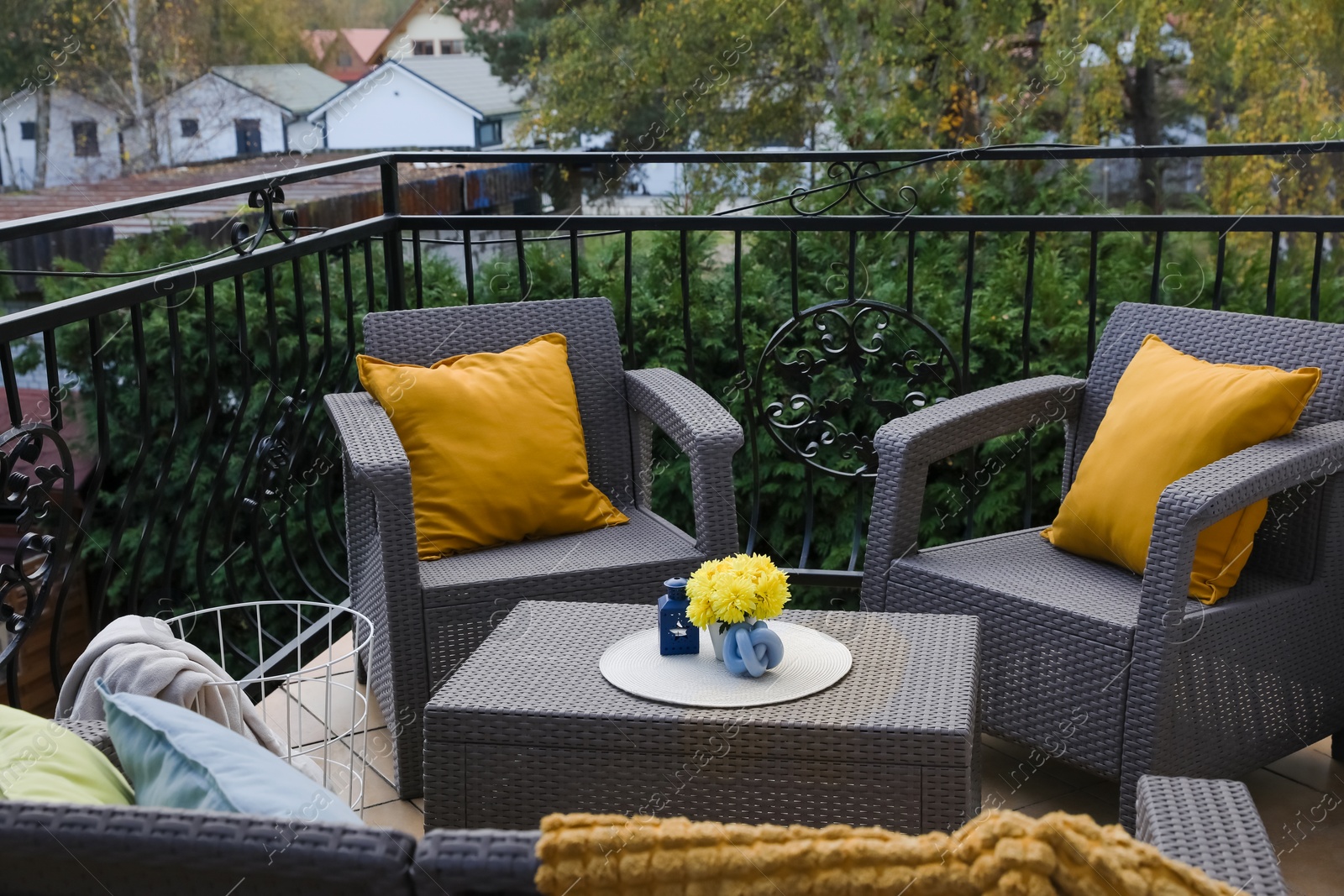 Photo of Orange pillows and yellow chrysanthemum flowers on rattan garden furniture outdoors