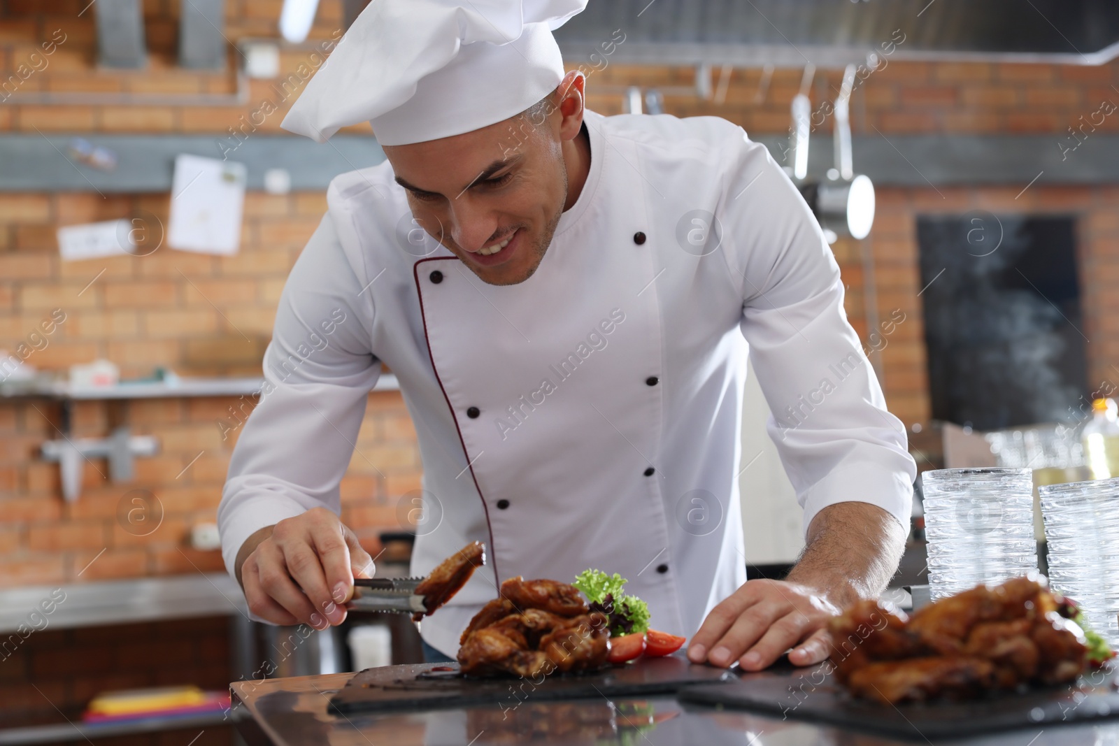 Photo of Professional chef with delicious fried chicken wings in restaurant kitchen