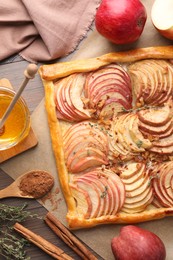 Photo of Freshly baked apple pie with nuts and ingredients on wooden table, flat lay
