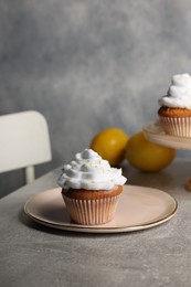 Delicious cupcakes with cream and lemon zest on gray table, space for text
