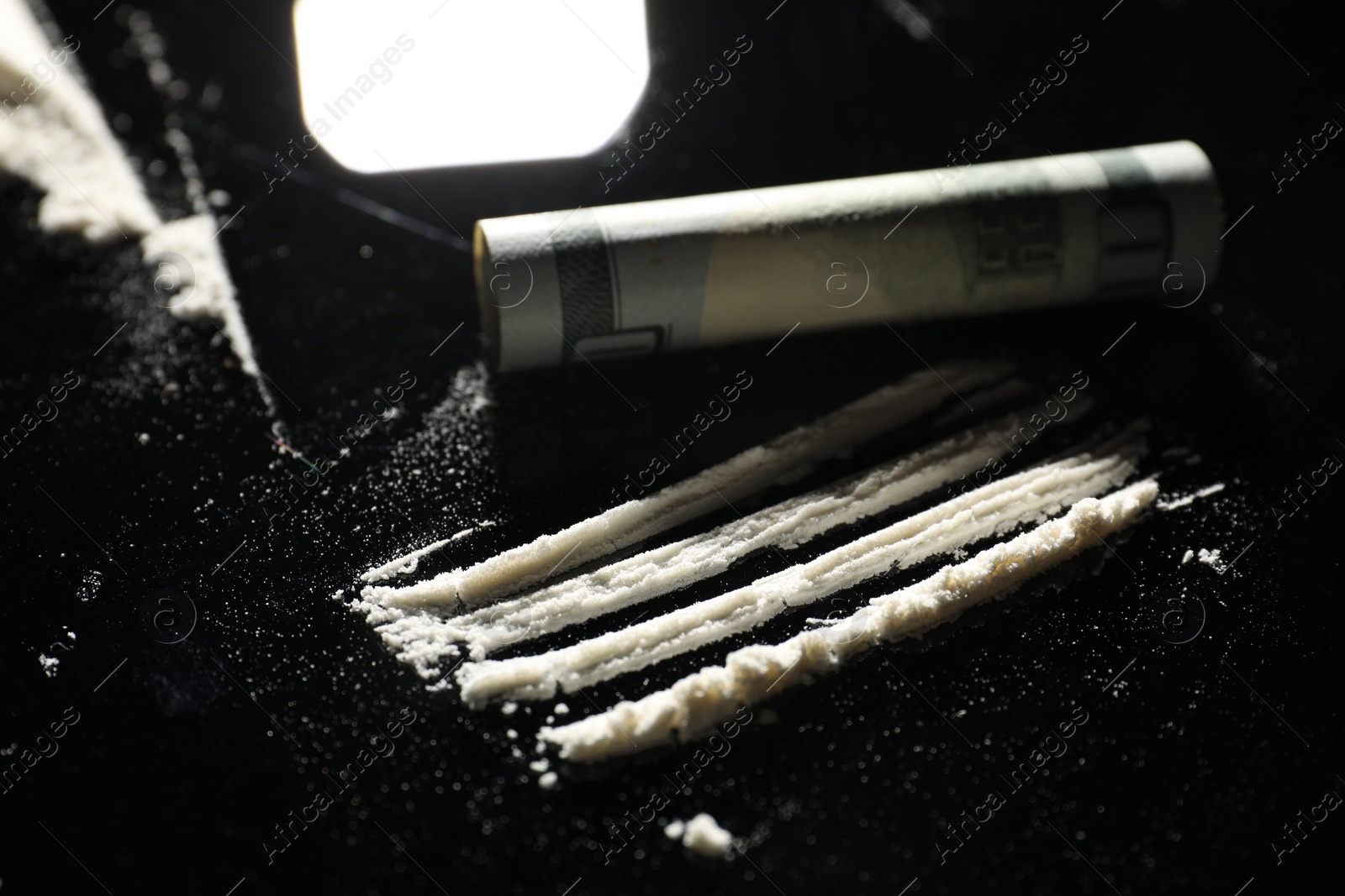 Photo of Drug addiction. Cocaine and rolled dollar banknote on black table, closeup