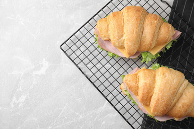 Tasty croissant sandwiches with ham on grey table, top view. Space for text