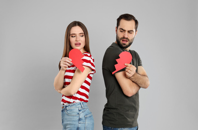 Couple with torn paper heart on grey background. Relationship problems