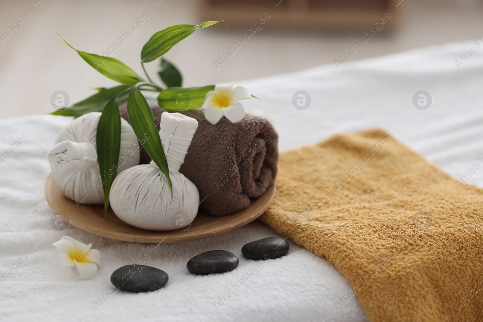 Photo of Spa stones, flowers and herbal bags on towel indoors