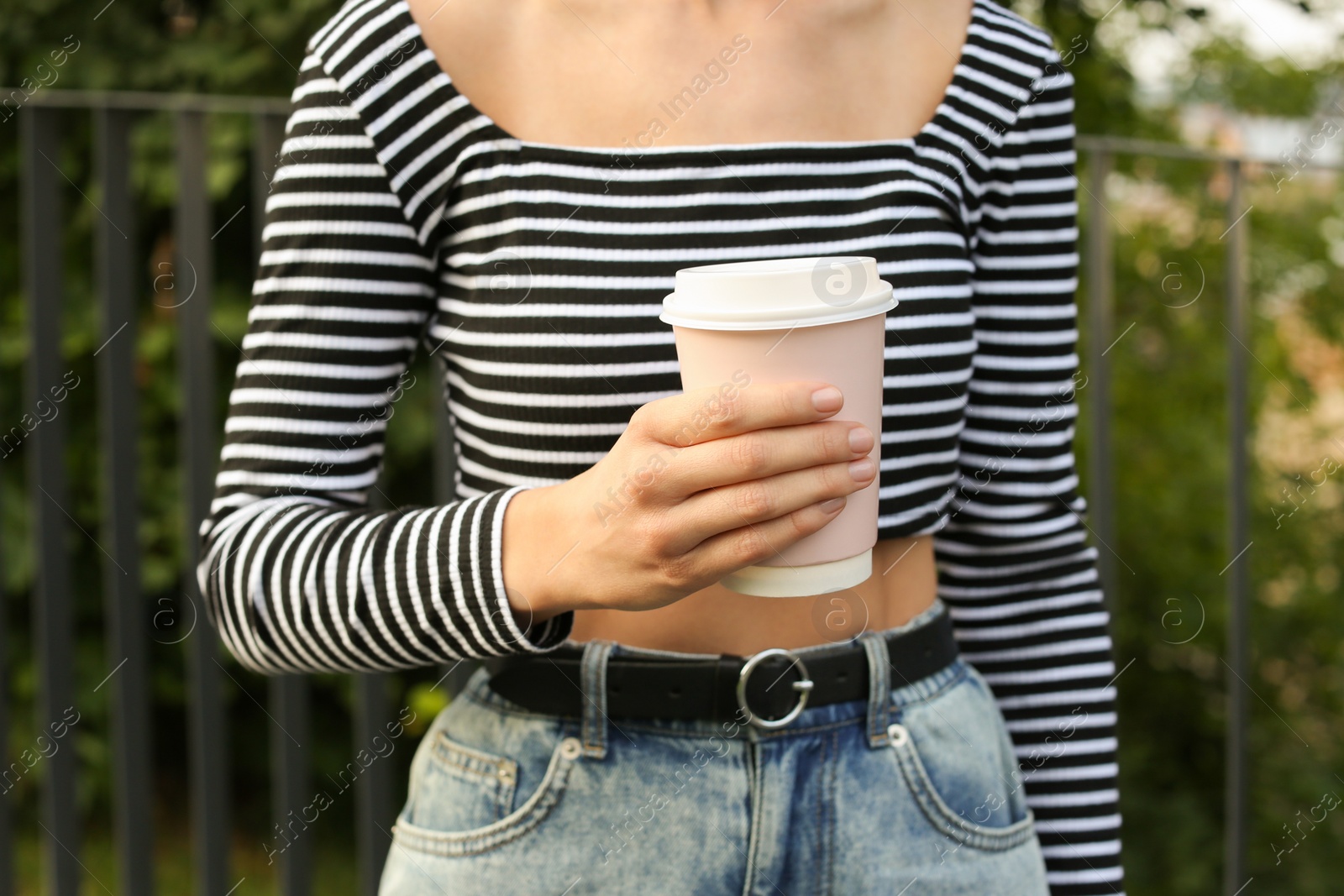 Photo of Coffee to go. Woman with paper cup of drink outdoors, closeup