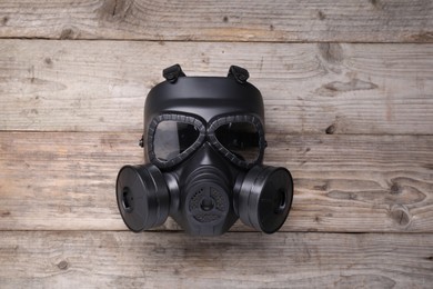 Photo of One gas mask on wooden background, top view