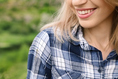 Photo of Young smiling woman in plaid shirt outdoors