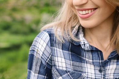 Young smiling woman in plaid shirt outdoors