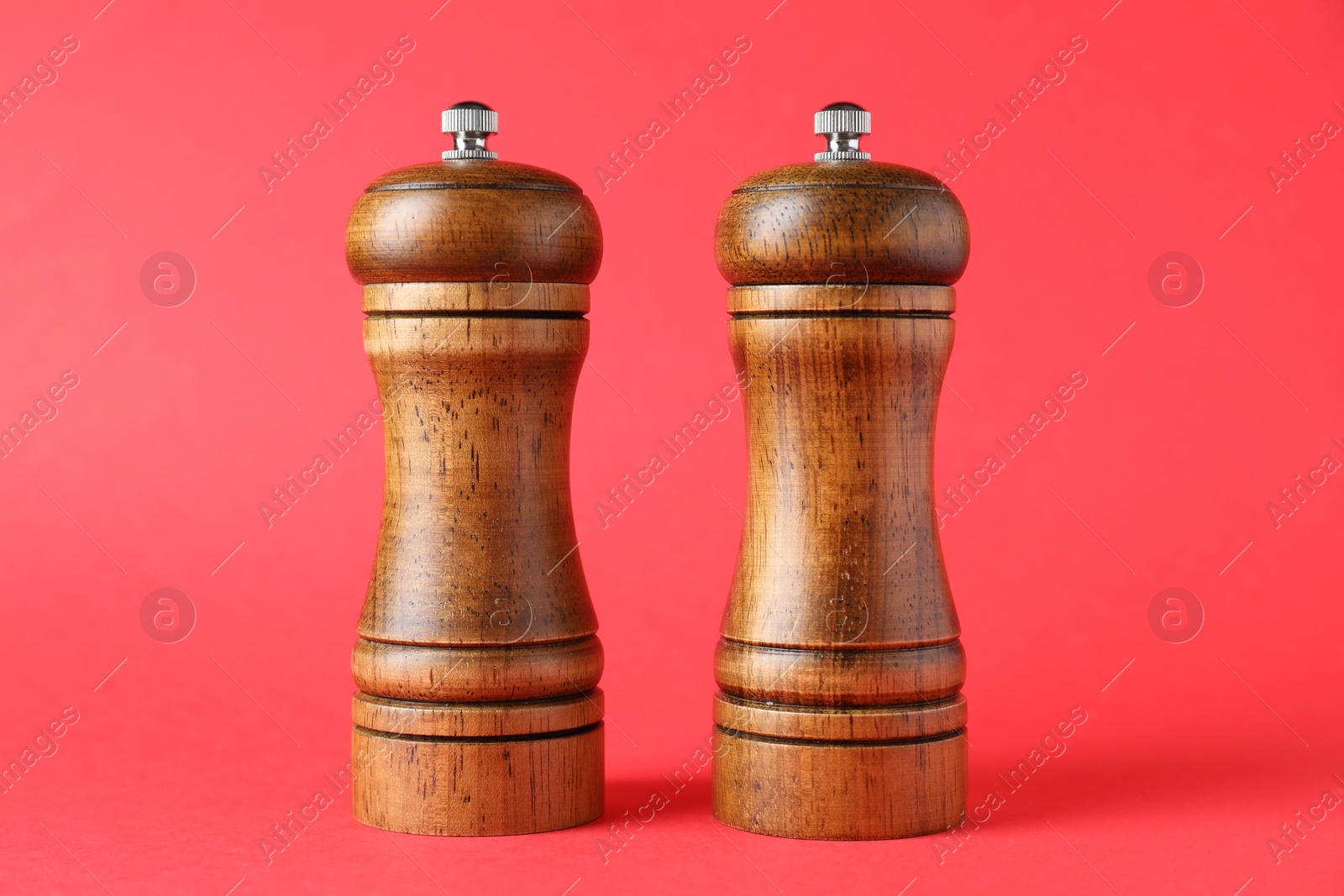 Photo of Wooden salt and pepper shakers on red background, closeup