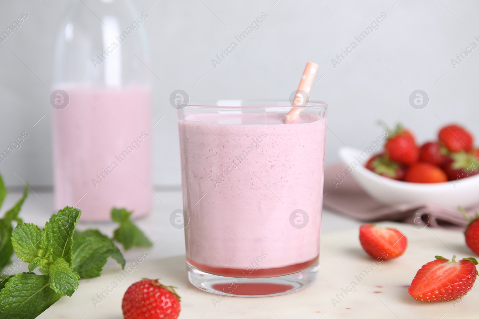 Photo of Tasty milk shake with strawberries and mint on table