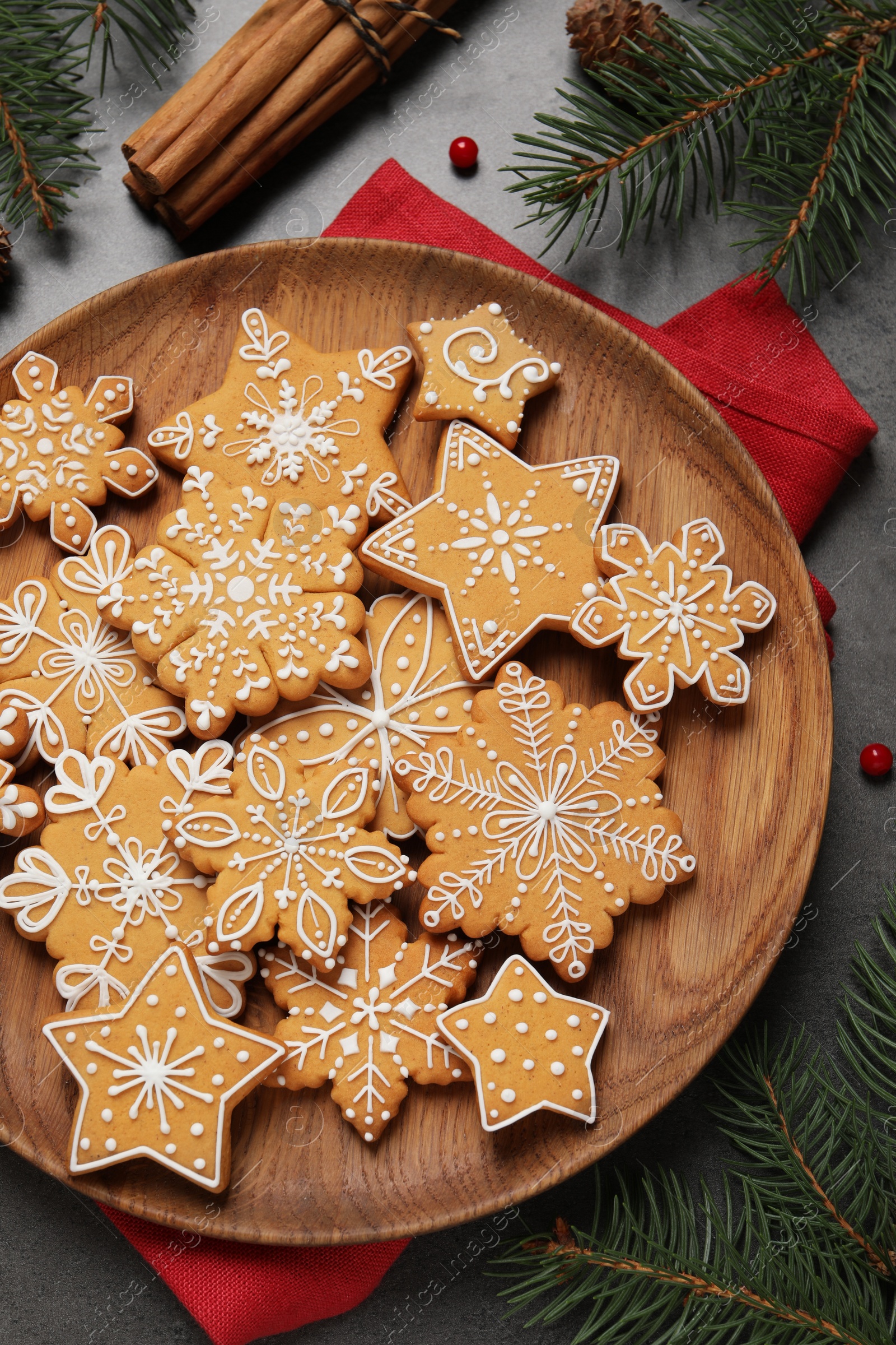 Photo of Tasty Christmas cookies, cinnamon and fir branches on grey table, flat lay