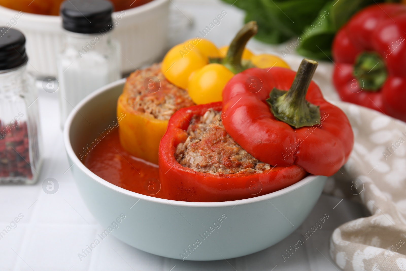 Photo of Delicious stuffed bell peppers on white tiled table, closeup