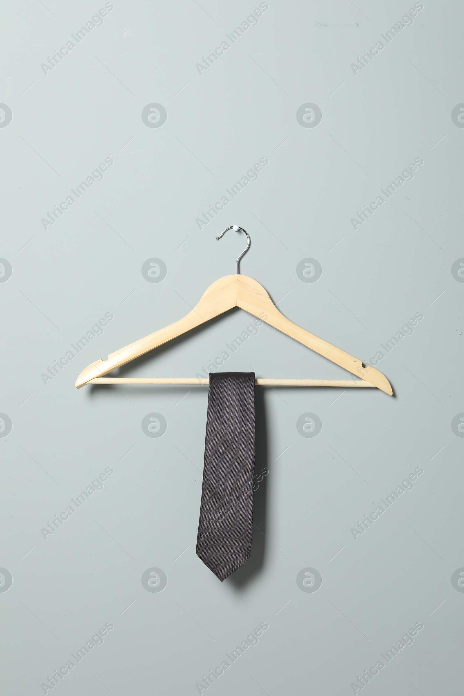 Photo of Hanger with necktie on light grey wall