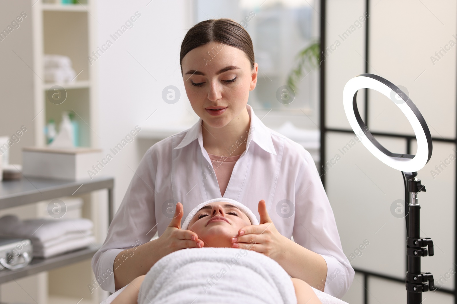 Photo of Cosmetologist making face massage to client in clinic