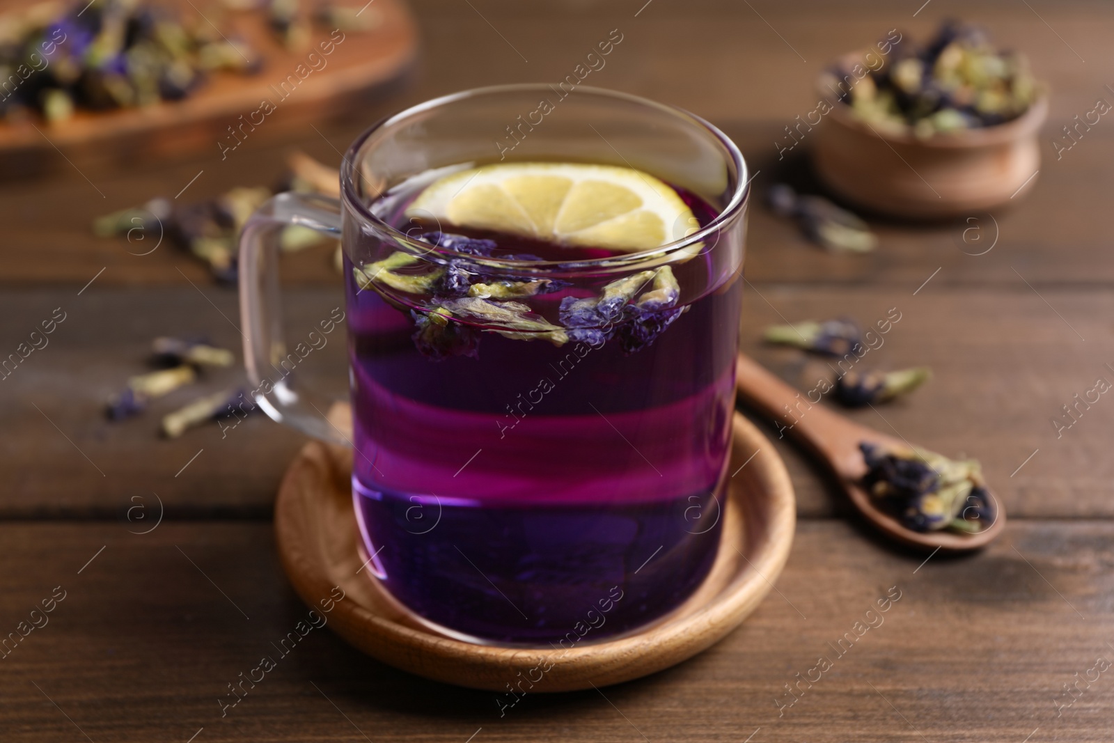 Photo of Glass mug of organic blue Anchan with lemon on wooden table. Herbal tea