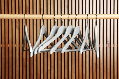 Photo of Empty hangers on rail against wooden background