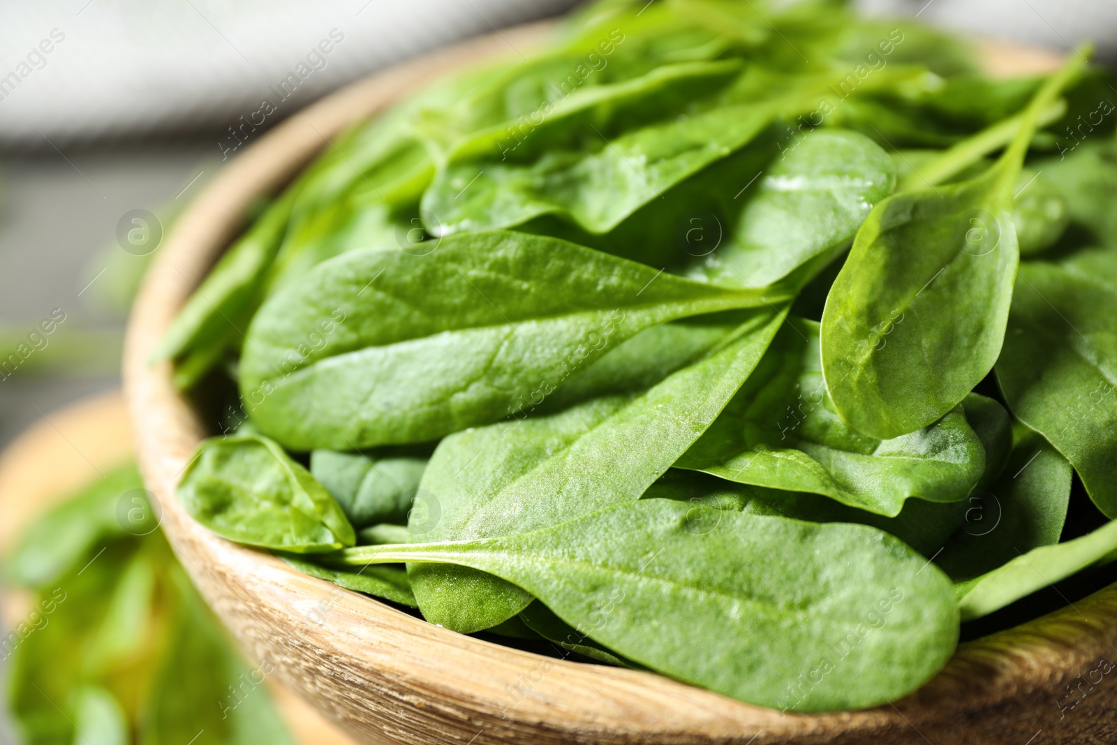 Photo of Fresh green healthy spinach in wooden bowl, closeup