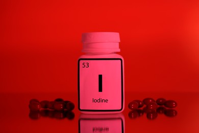 Photo of Bottlemedical iodine and pills on red background, color tone effect