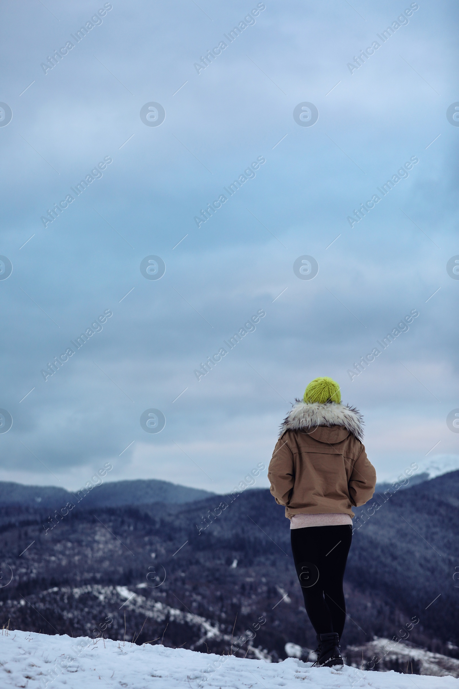 Photo of Woman in warm clothes enjoying mountain landscape. Winter vacation