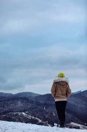 Photo of Woman in warm clothes enjoying mountain landscape. Winter vacation