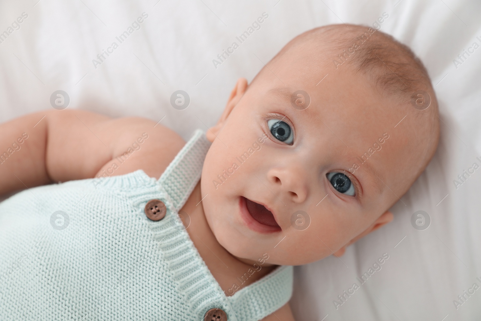 Photo of Cute little baby lying on white blanket, top view