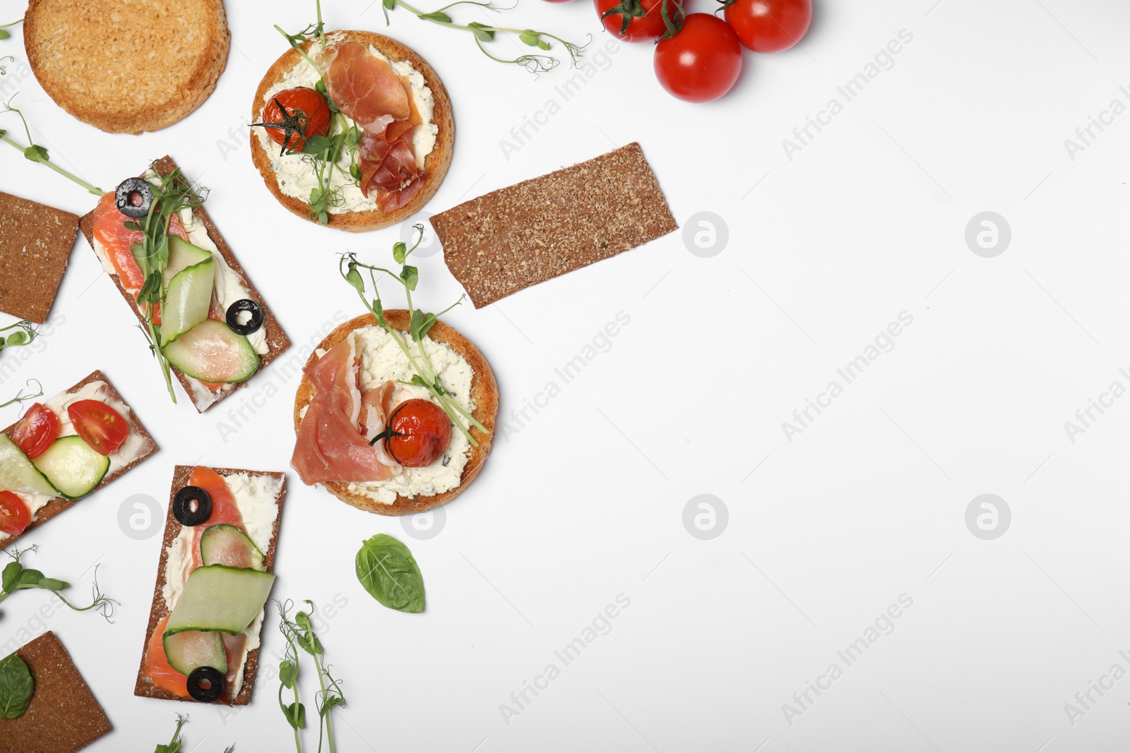 Photo of Tasty rusks and rye crispbreads with different toppings on white background, top view