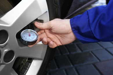 Mechanic checking tire air pressure at car service, closeup