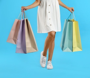 Photo of Young woman with paper shopping bags on light blue background, closeup