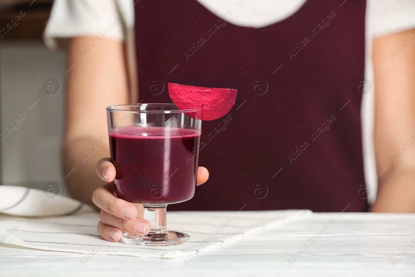 Photo of Woman with glass of beet smoothie at table, closeup