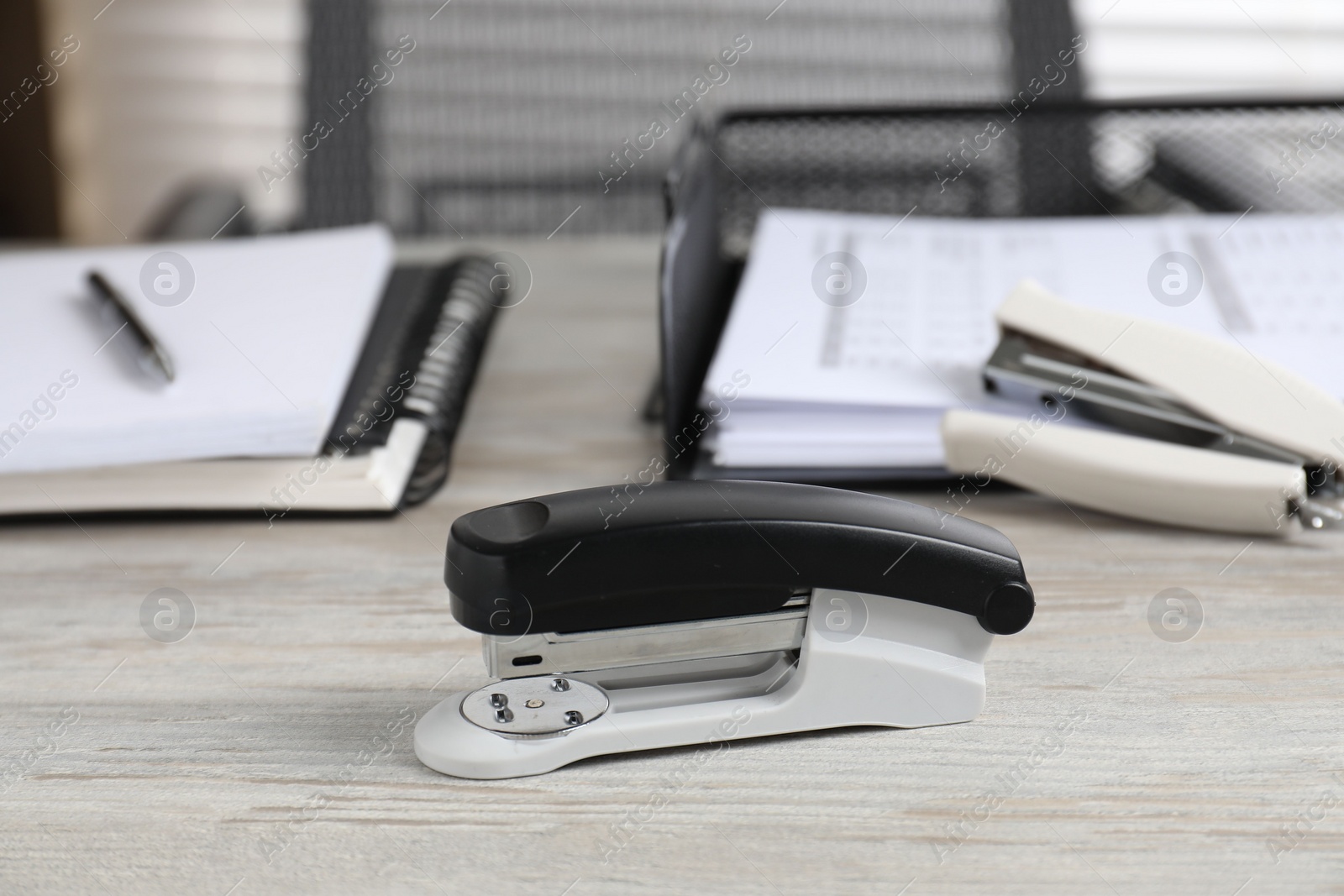 Photo of Stapler on wooden table, closeup. Office stationery