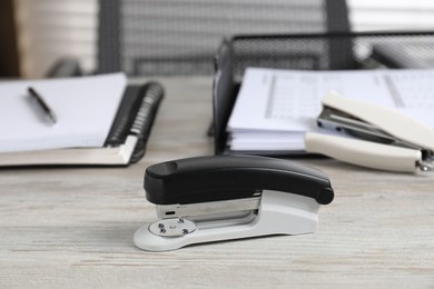 Stapler on wooden table, closeup. Office stationery