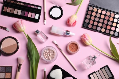 Photo of Flat lay composition with different makeup products and beautiful spring flowers on pink background