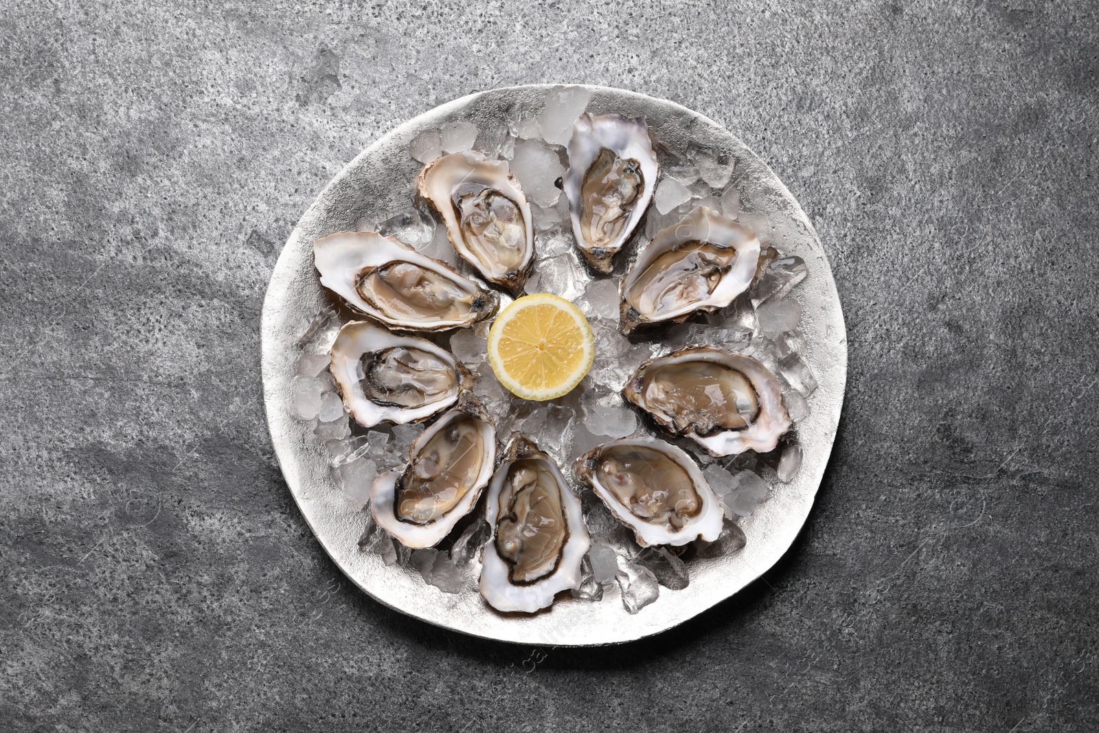 Photo of Delicious fresh oysters with lemon on grey table, top view