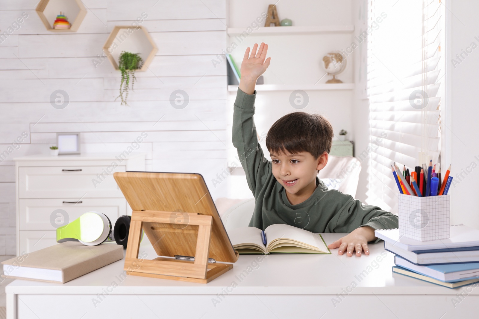 Photo of Cute little boy with modern tablet studying online at home. E-learning