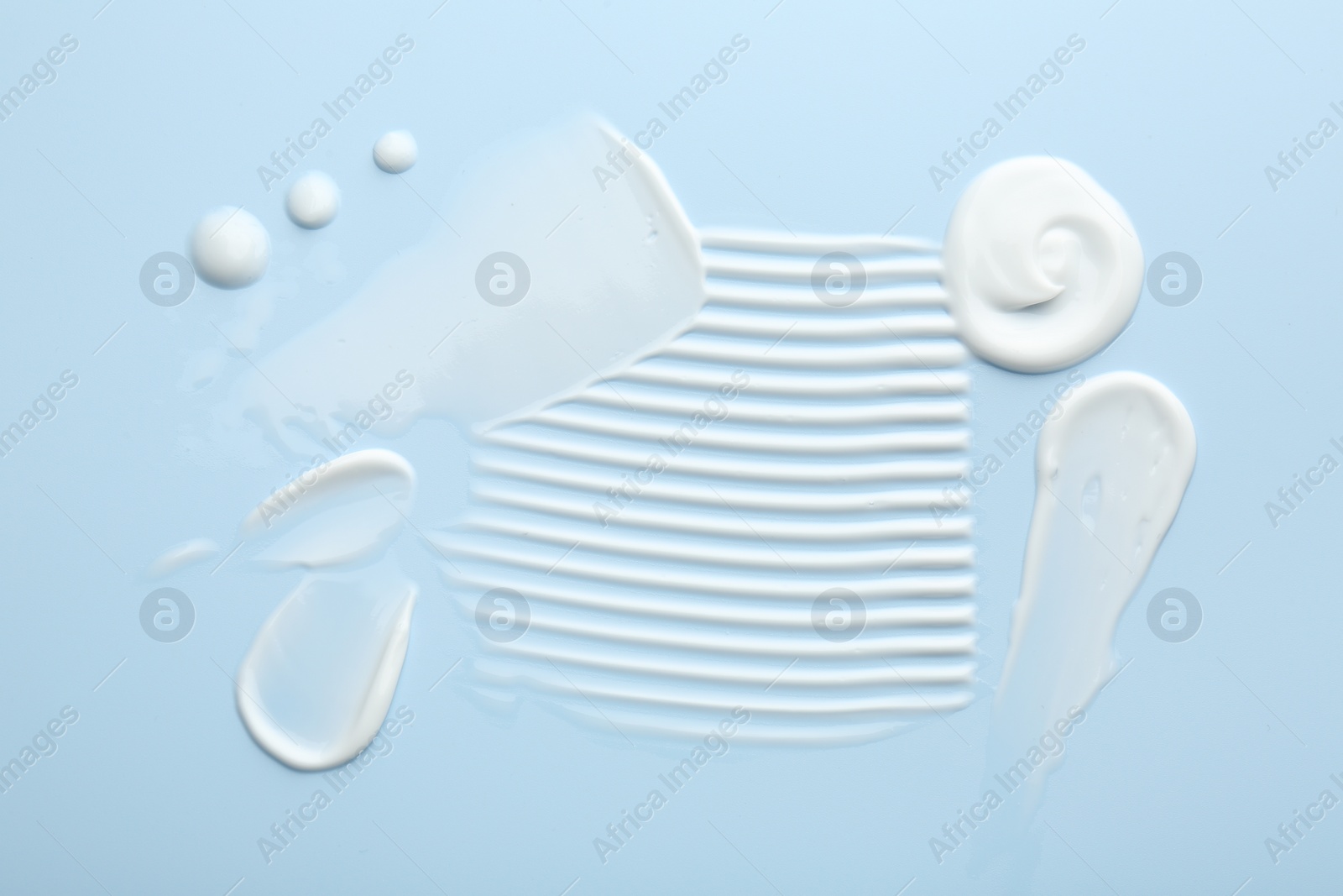 Photo of Samples of face cream on light blue background, top view