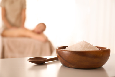Bowl with sea salt on white table in spa salon