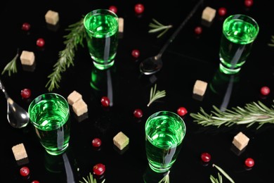 Photo of Absinthe in shot glasses, cranberries, rosemary and brown sugar on mirror table. Alcoholic drink
